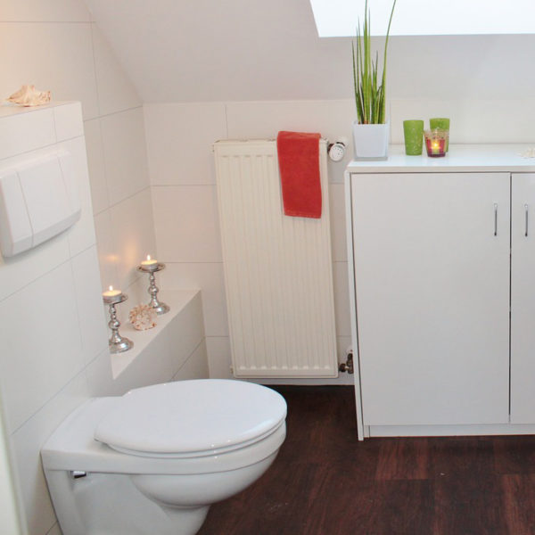 All white bathroom with toilet, candles and bright green and red decor